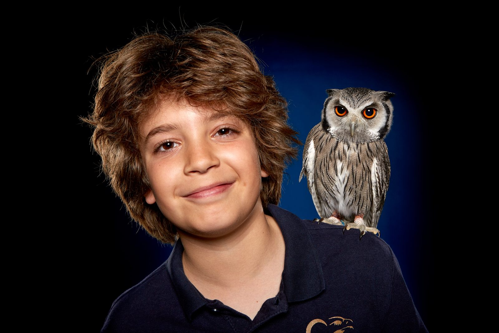 Retrato de estudio de un niño con un autillo posado en el hombro